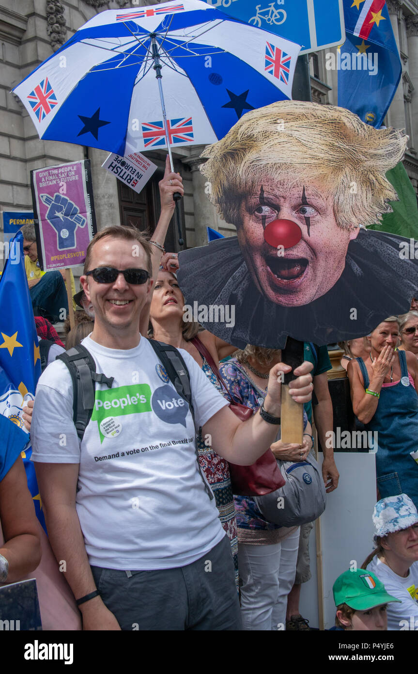 Londra, Regno Unito. Il 23 giugno 2018. Un uomo detiene un pauroso Boris Johnson come un clown come egli vigila il rally sulla schermata di overflow in Whitehall. Più di centomila persone hanno marciato attraverso Londra a sostegno di un voto popolare su qualsiasi Brexit finale della trattativa. Ci sono stati troppi per entrare in Piazza del Parlamento che è stato imballato quando il rally avviato nonostante la fine del marzo essendo riportato ancora non hanno lasciato il punto di partenza in Pall Mall. Molti hanno guardato il rally su di uno schermo gigante in fondo Whitehall. La manifestazione è stata organizzata da gruppi tra cui sano nella UE, accordo commerciale guarda la Gran Bretagna per l'Europa, Foto Stock