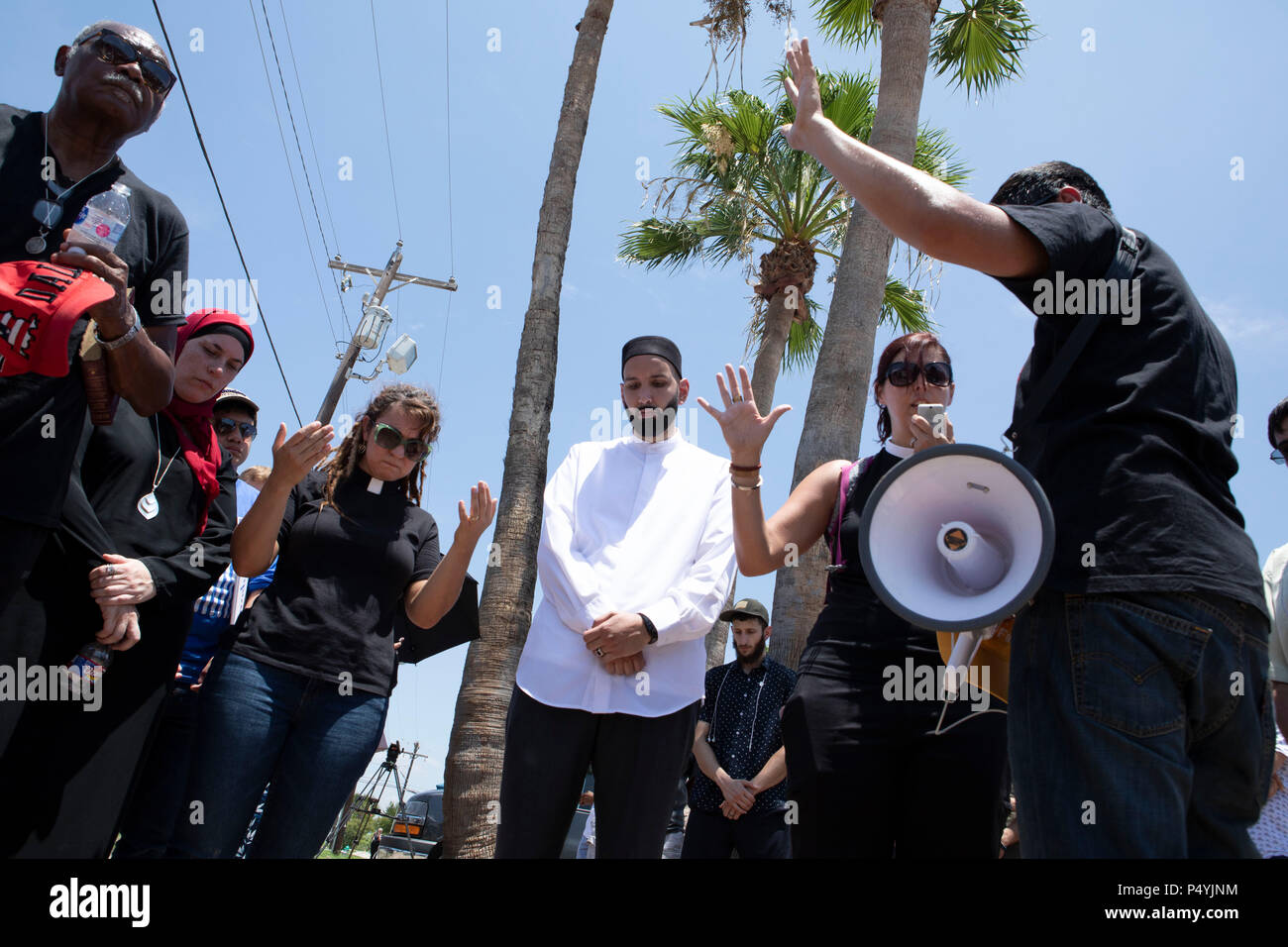 Il clero di diverse confessioni pregano come Stati Uniti Pattuglia di Confine e McAllen Guardia di polizia un immigrato centro di detenzione come manifestanti blocco un governo bus con figli di immigrati a bordo da lasciare. Foto Stock