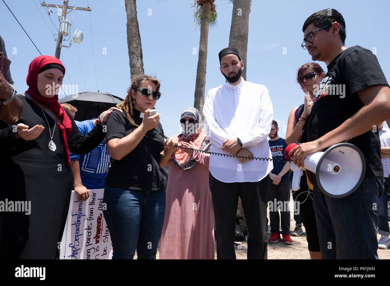 Il clero di diverse confessioni pregano come Stati Uniti Pattuglia di Confine e McAllen Guardia di polizia un immigrato centro di detenzione come manifestanti blocco un governo bus con figli di immigrati a bordo da lasciare. Foto Stock