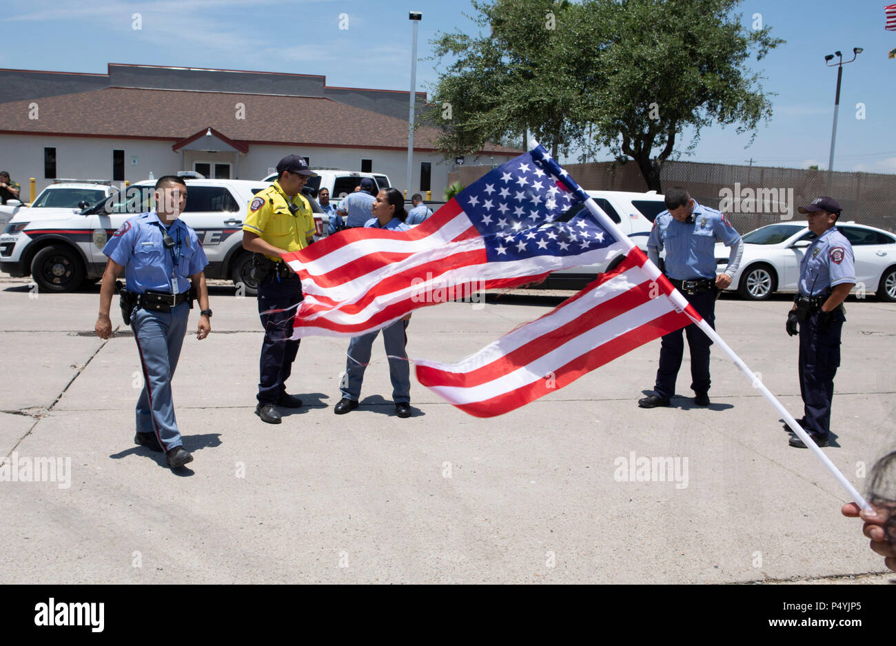 Stati Uniti Pattuglia di Confine e McAllen Guardia di polizia un immigrato centro di detenzione mentre i manifestanti blocco un governo bus con figli di immigrati a bordo per tenerlo da lasciare. Foto Stock
