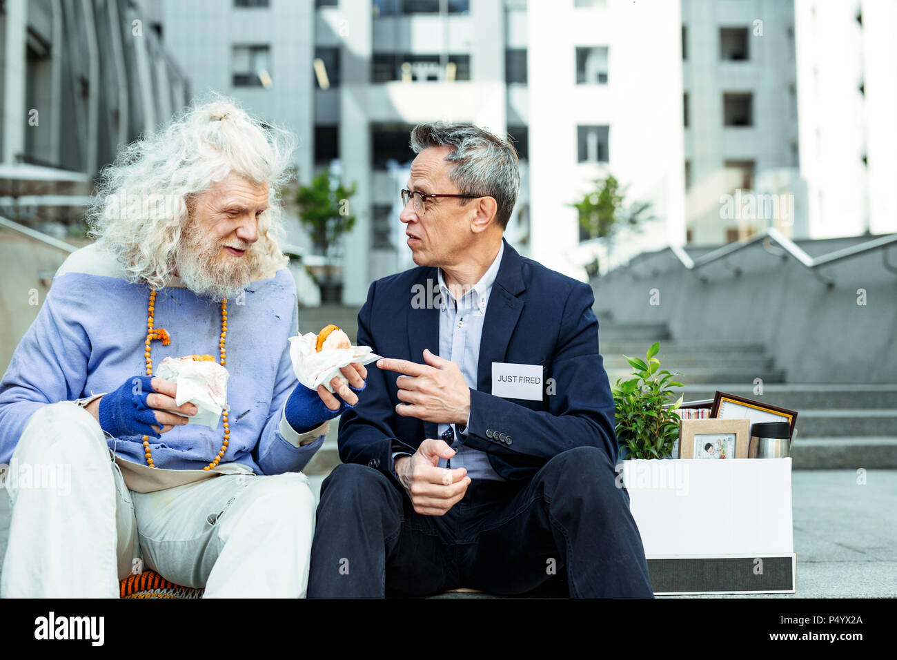 Ispirato hippy di mangiare hamburger fuori insieme con appena licenziato uomo Foto Stock