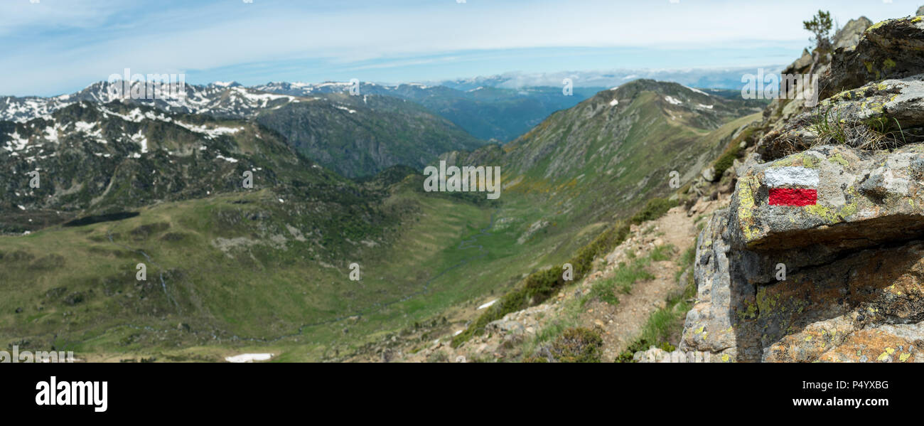 Il bianco e il rosso modo segno di marcatore dipinta su una roccia nei Pirenei francesi accanto a un sentiero sulla GR10 escursionismo prova, con una vista panoramica Foto Stock