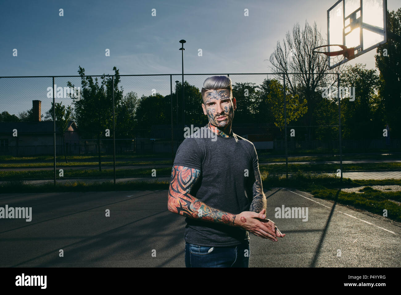 Ritratto di tatuati giovane uomo sul campo di pallacanestro Foto Stock