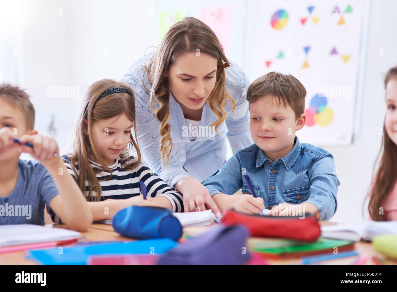 Docente aiutare gli studenti con i loro compiti in classe Foto Stock