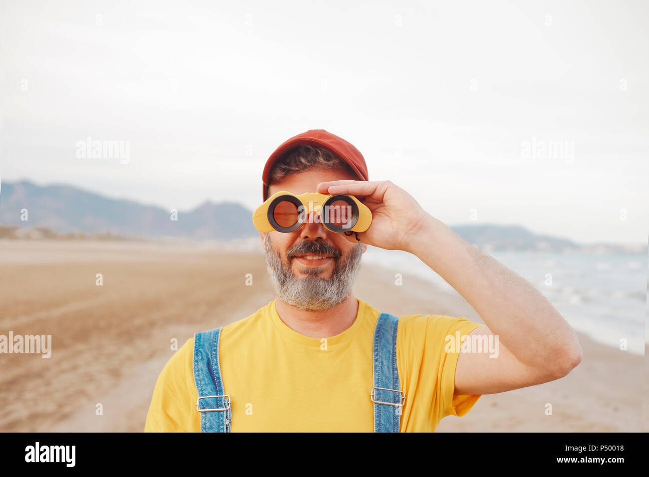 Uomo Barbuto con il binocolo sulla spiaggia Foto Stock