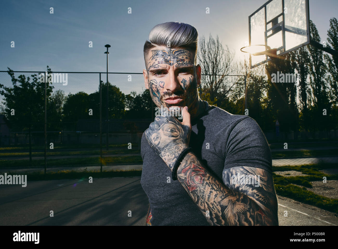 Ritratto di tatuati giovane uomo sul campo di pallacanestro Foto Stock