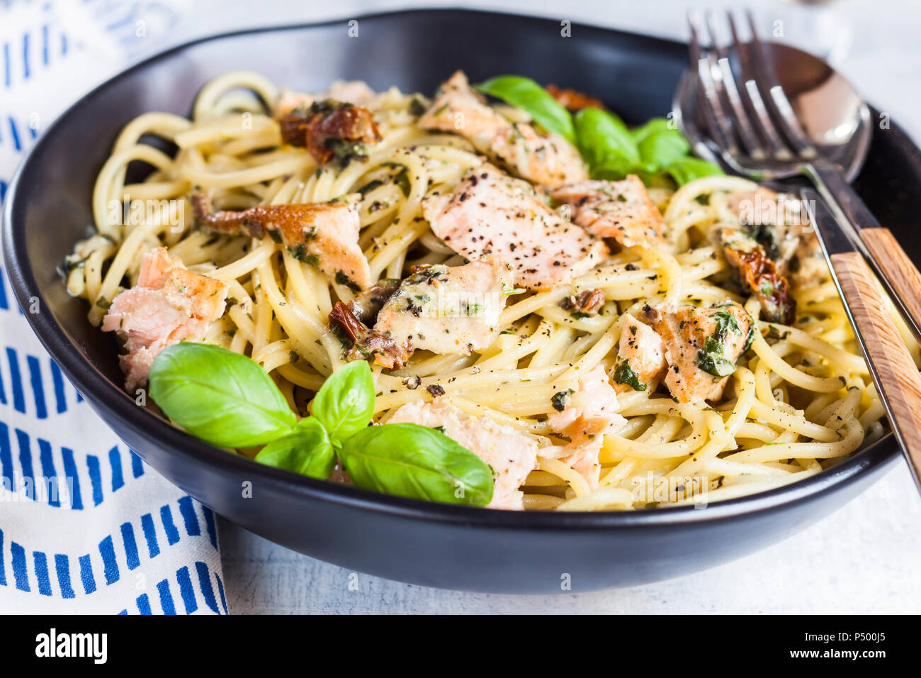 Spaghetti con crema di spinaci, salsa di pomodori secchi e salmone Foto Stock