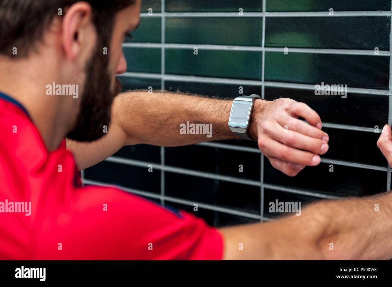 L'uomo avente una pausa dall'esecuzione controllando il tempo su un smartwatch Foto Stock