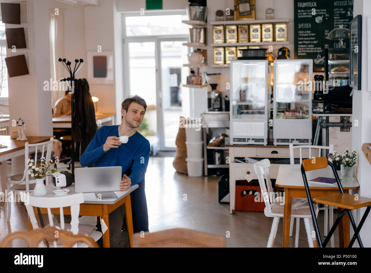 Uomo seduto a tavola in un cafe con il computer portatile Foto Stock