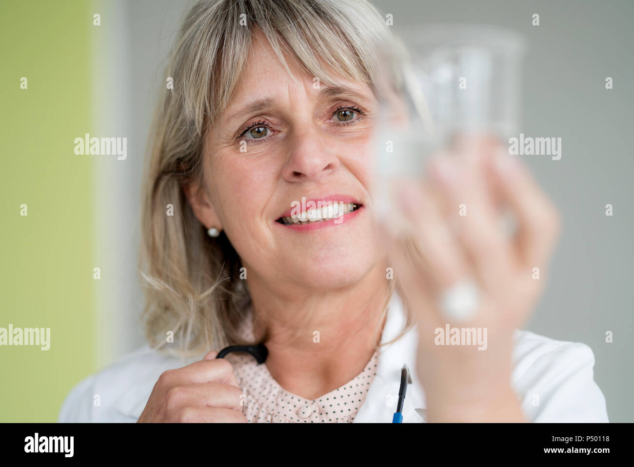 Sorridente donna matura tenendo un bicchiere di acqua Foto Stock