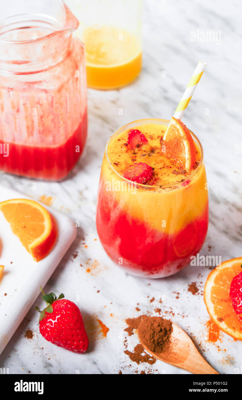 La fragola e orange smoothie con curcuma e cannella su marmo Foto Stock