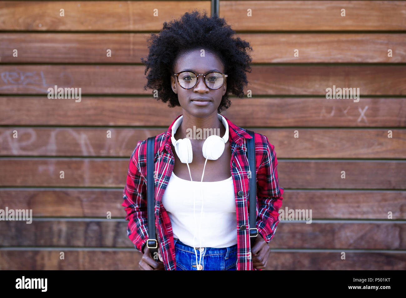 Ritratto di giovane donna con zaino e le cuffie nella parte anteriore della parete in legno Foto Stock