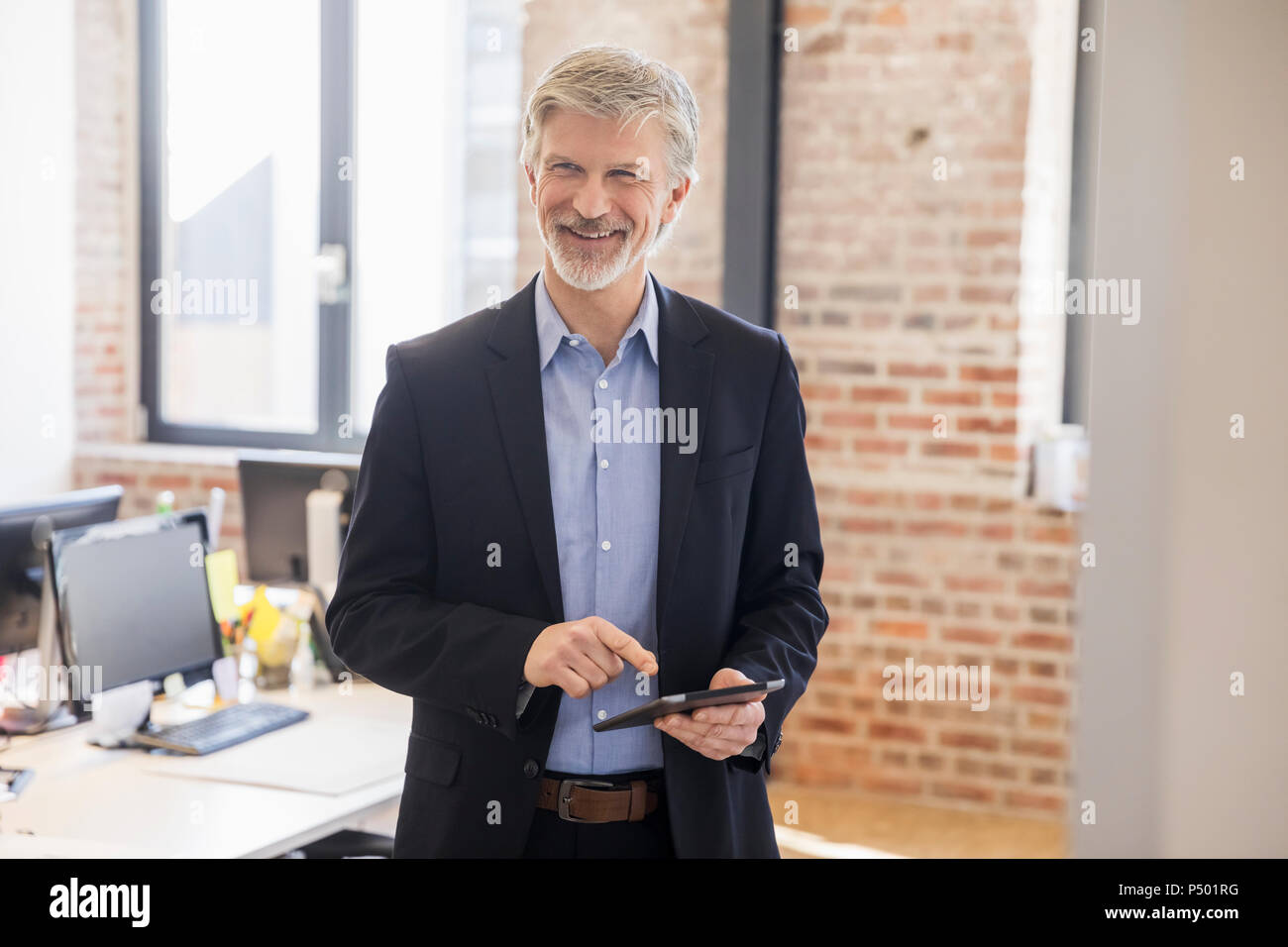 Uomo maturo in piedi nel suo ufficio, utilizzando didgital tablet Foto Stock