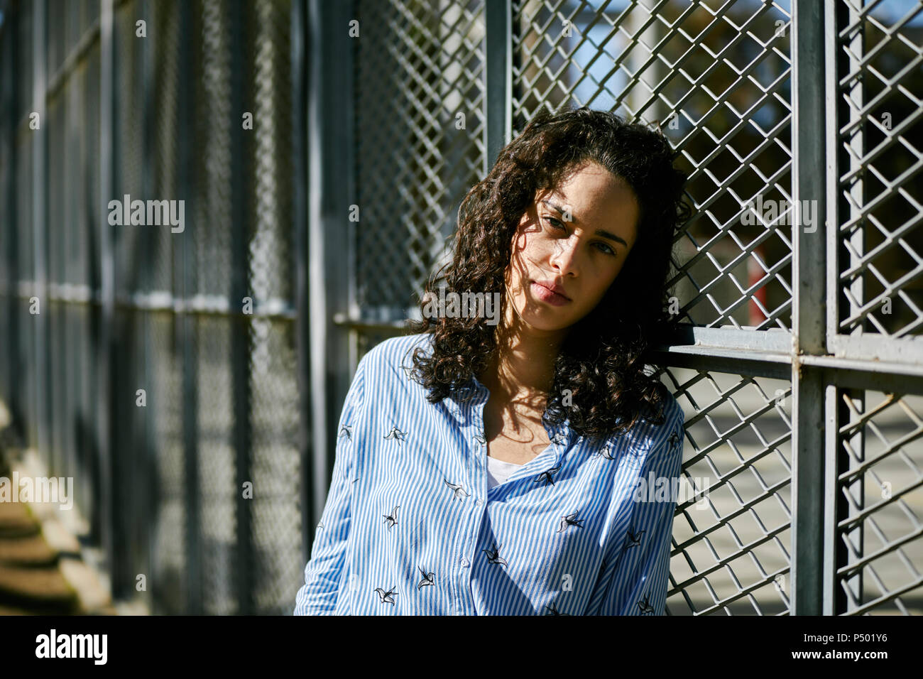 Ritratto di giovane e bella donna appoggiata contro una recinzione Foto Stock