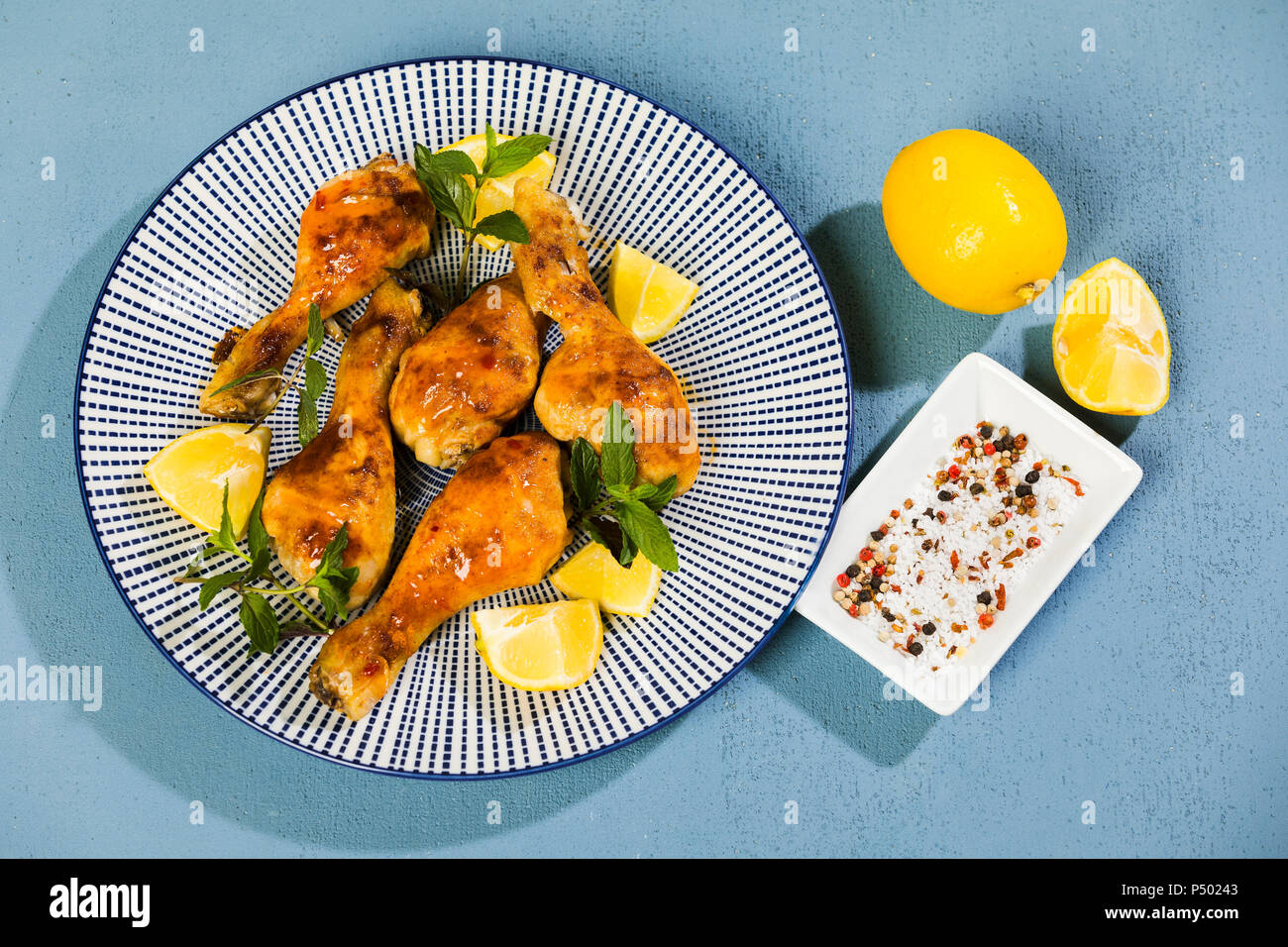 Il pollo al forno le gambe sull'ardesia, limone Foto Stock