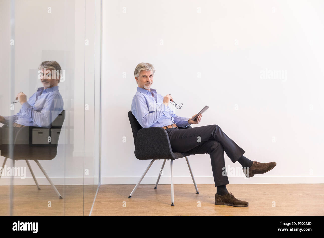 Imprenditore seduti su una sedia, utilizzando tavoletta digitale Foto Stock