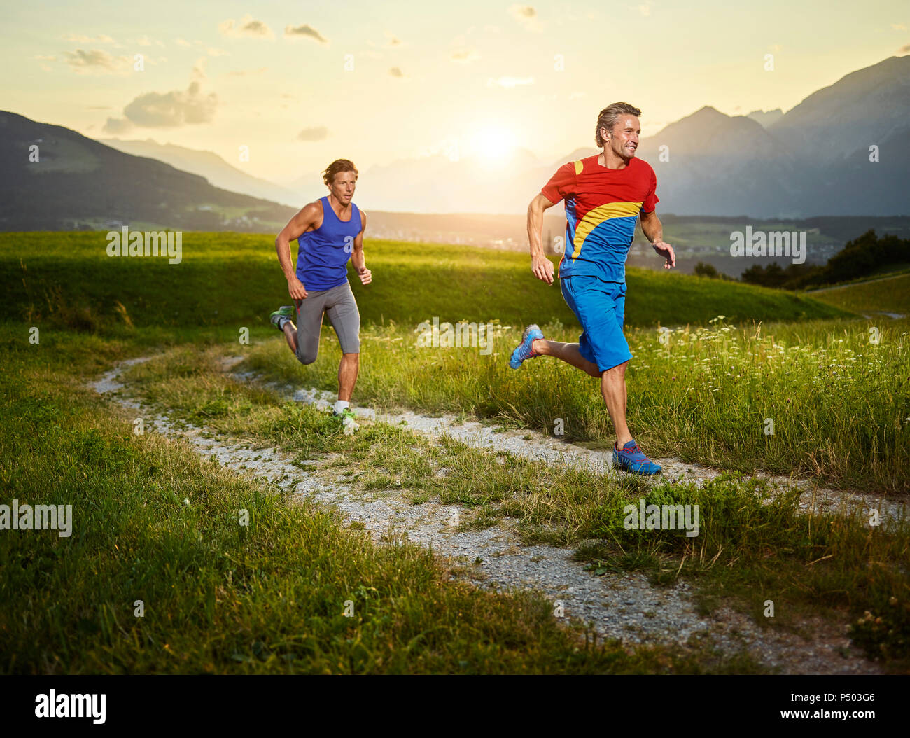 Due atleti in esecuzione sul percorso del campo al tramonto Foto Stock