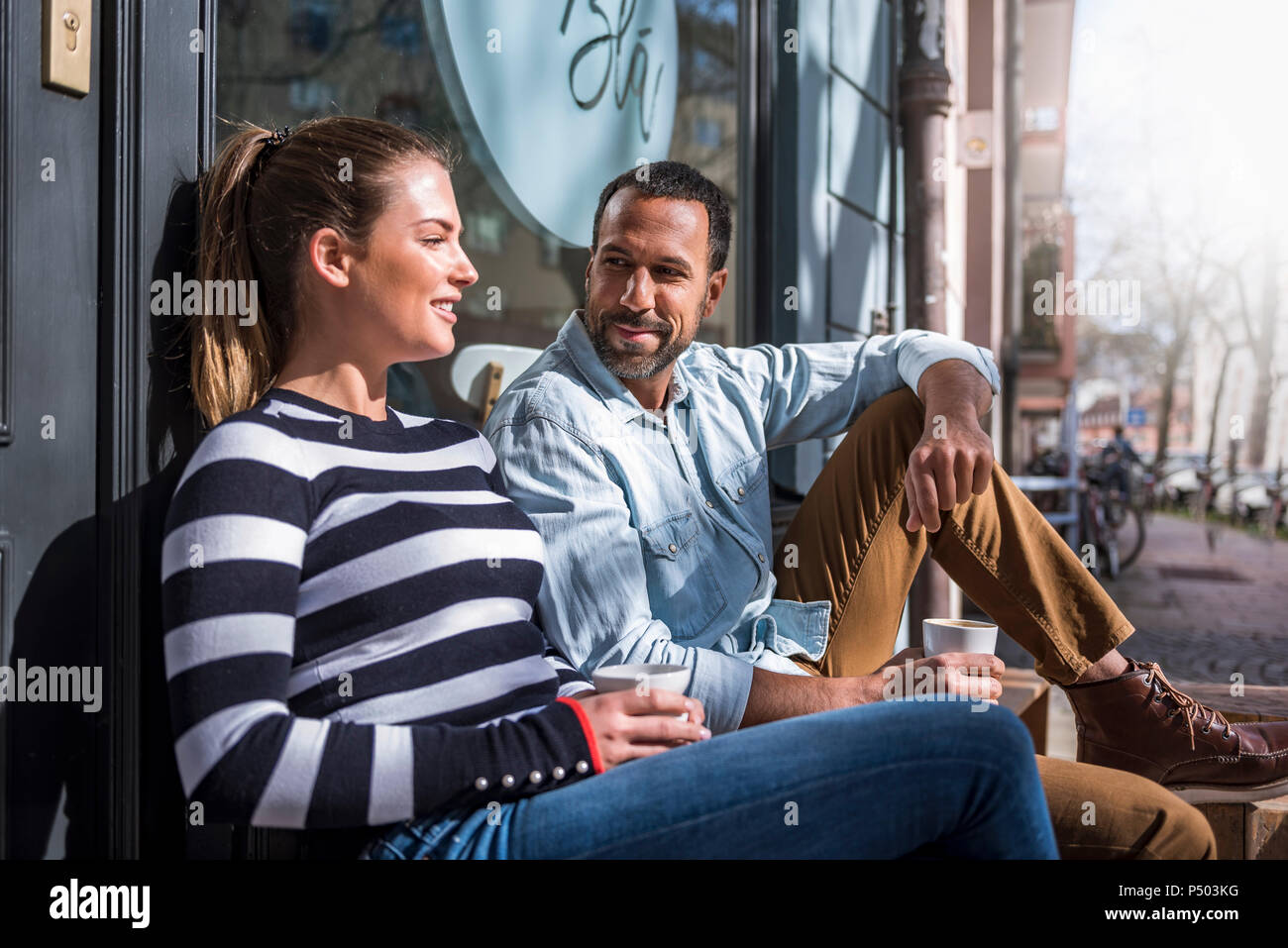 L uomo e la donna seduta al di fuori di un cafe parlando Foto Stock