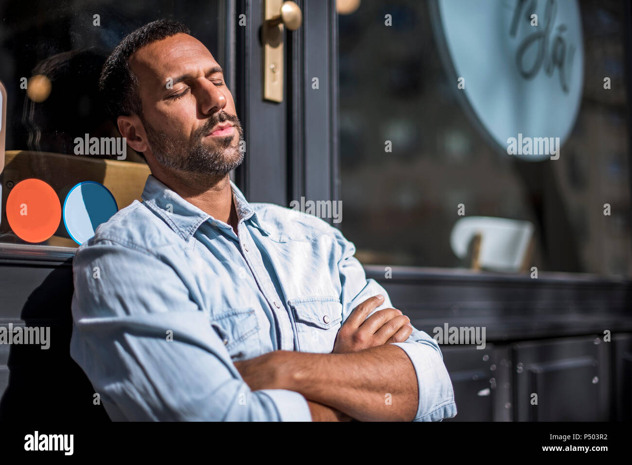 Uomo disteso al di fuori di un cafe godendo il sole Foto Stock