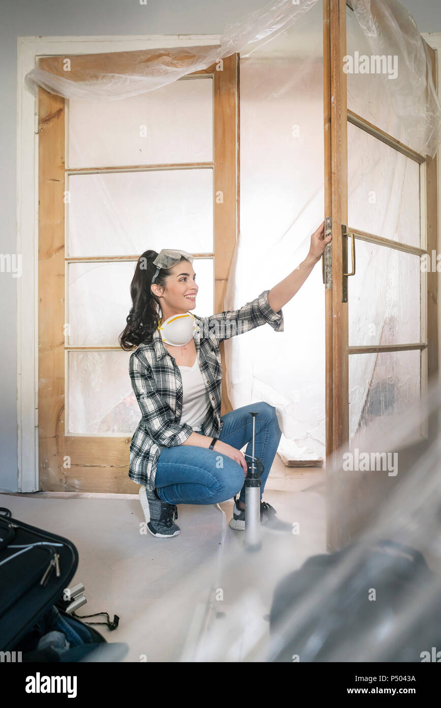 Giovane donna rinnovando il suo nuovo appartamento, esaminando la porta Foto Stock