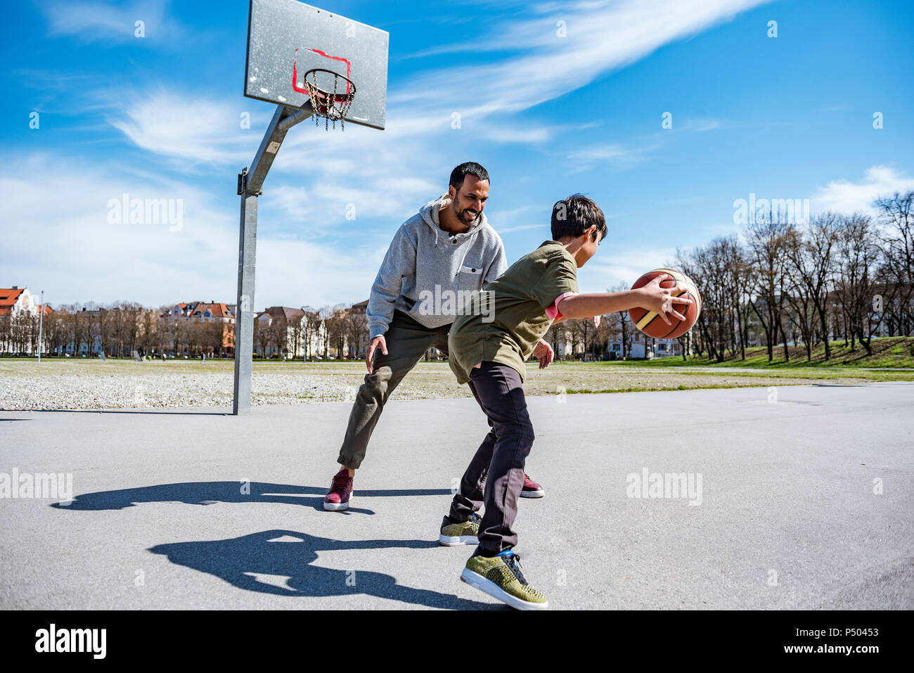 Padre e figlio giocare a basket sulla corte all'aperto Foto Stock