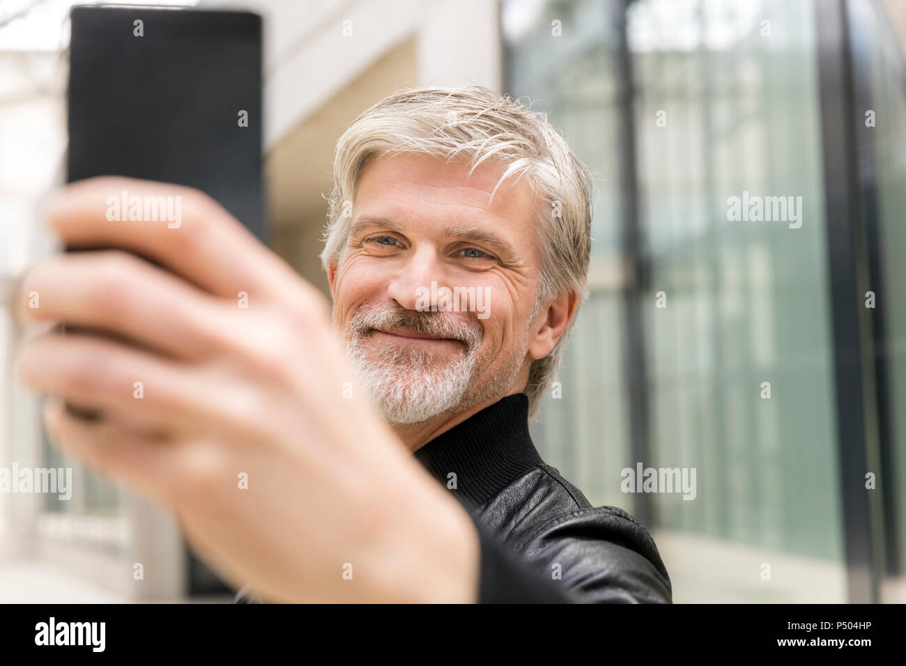 Uomo maturo tenendo selfies con il suo smartphone Foto Stock