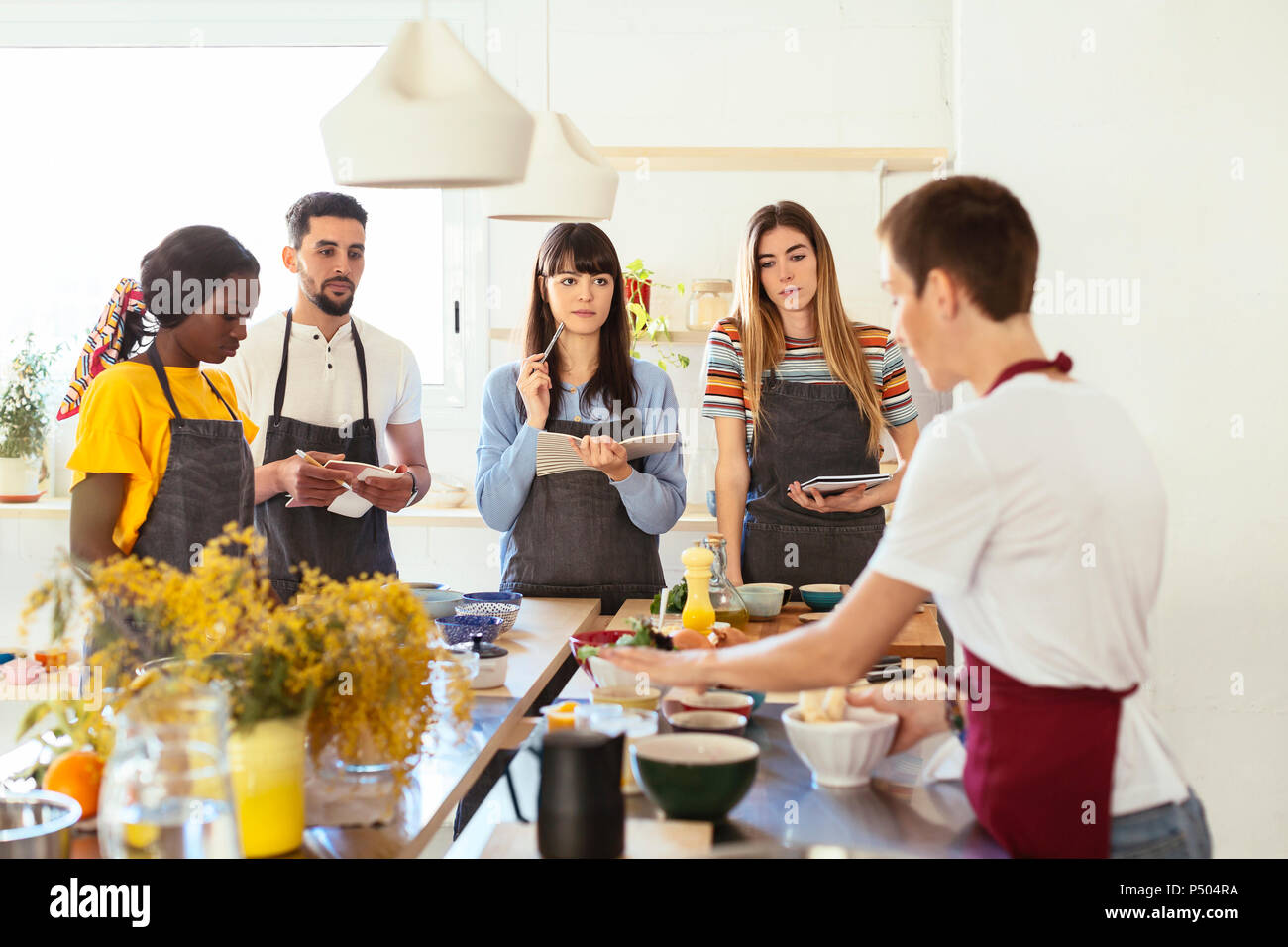 Amici in un laboratorio di cucina ascolto di istruttore Foto Stock