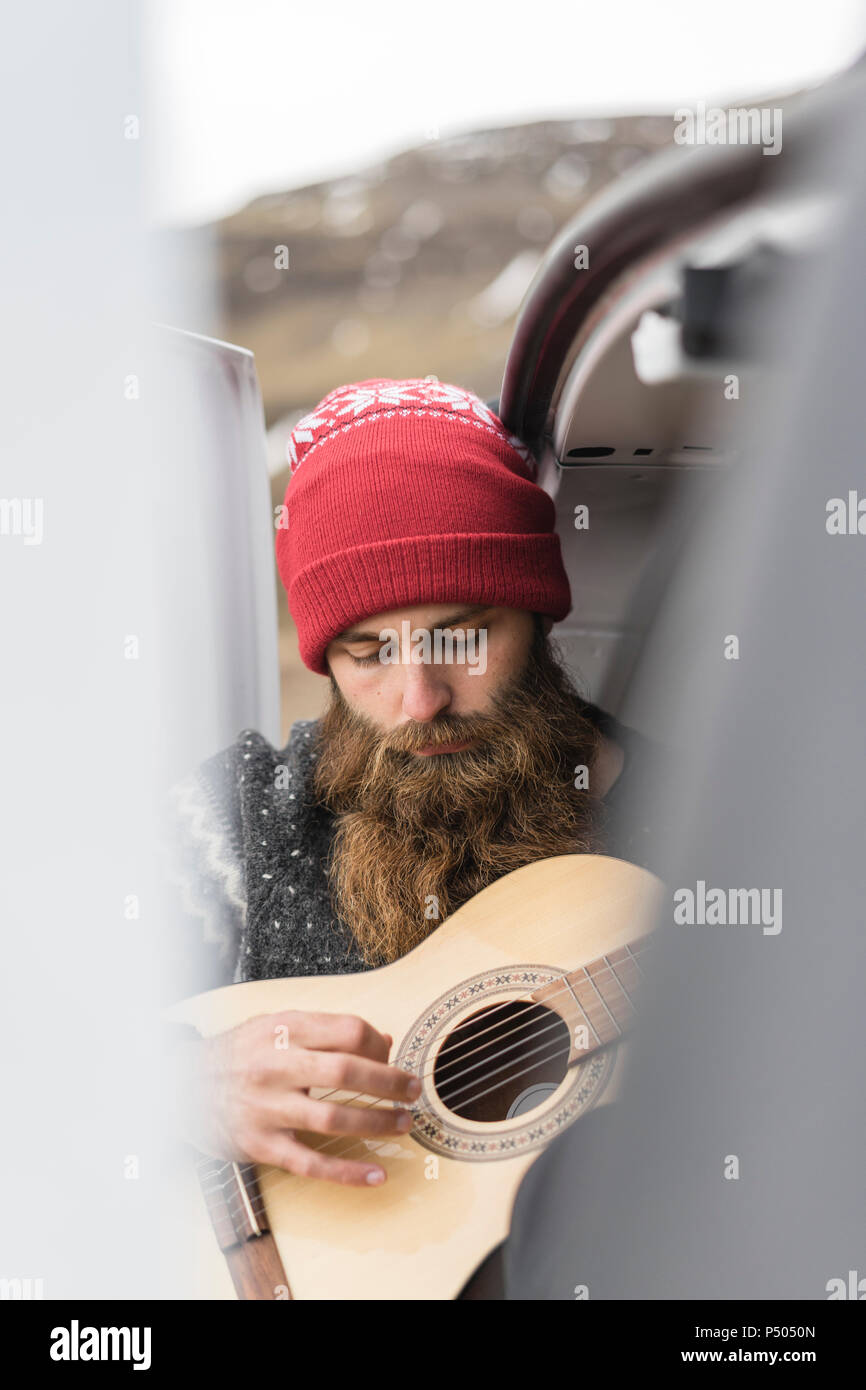 Ritratto di hipster indossando red cappellino a suonare la chitarra Foto Stock