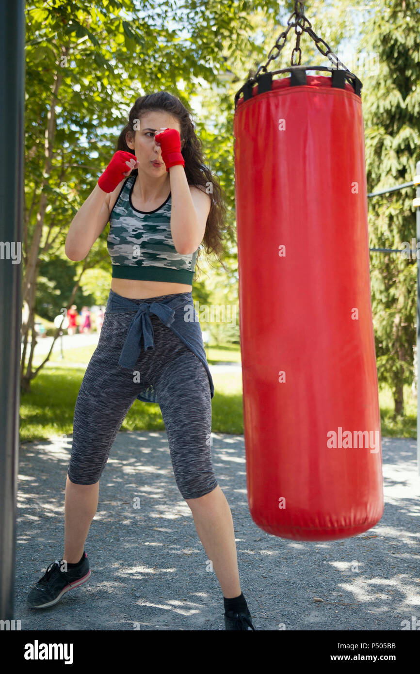 Attraente giovane donna in abbigliamento sportivo batte un sacco da boxe  Foto stock - Alamy