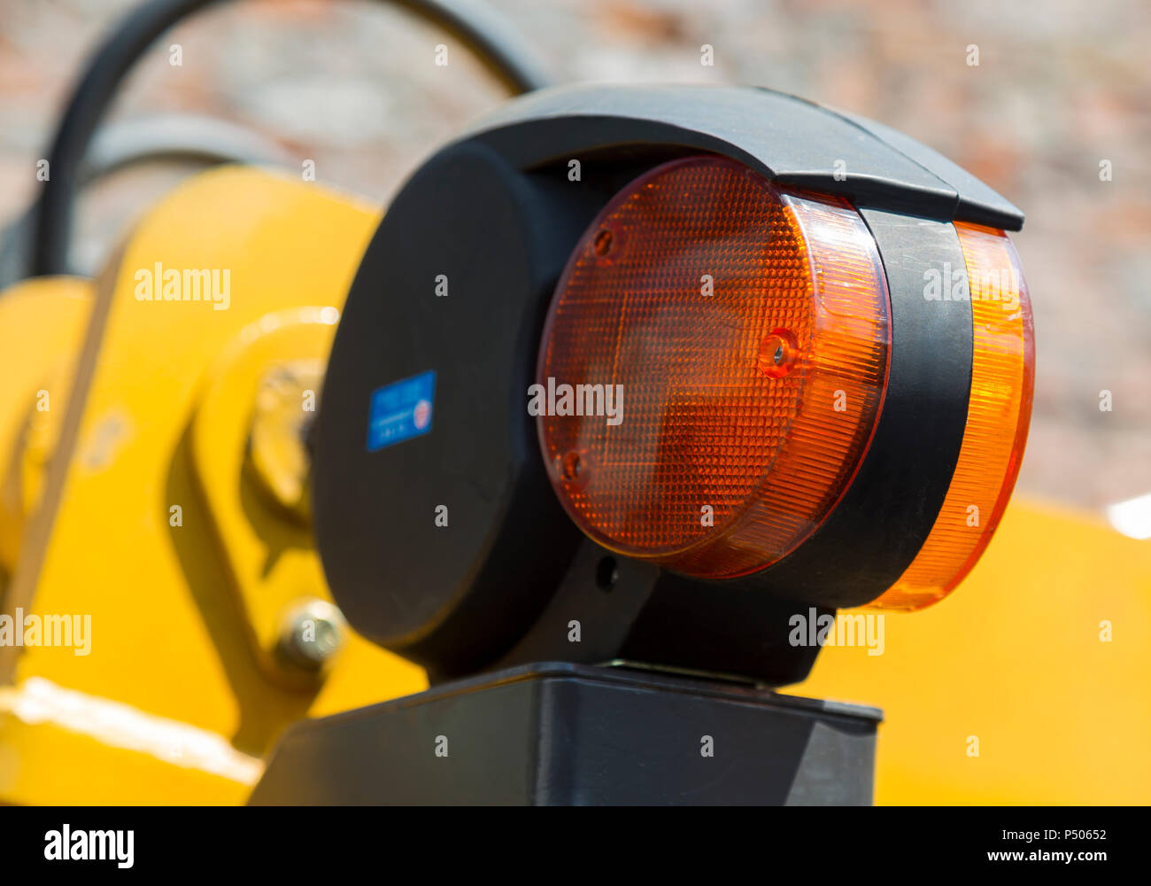 Avviso di liquidazione arancione luce del giallo macchine stradali close-up su sfondo sfocato dei suoi meccanismi, i tubi flessibili idraulici e il muro di mattoni Foto Stock