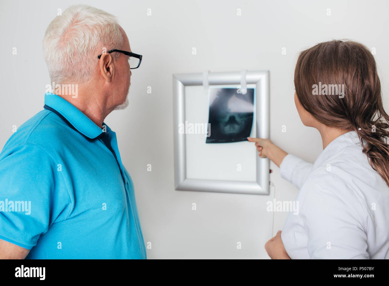 Medico la revisione delle immagini a raggi x con paziente anziano in ufficio medici Foto Stock