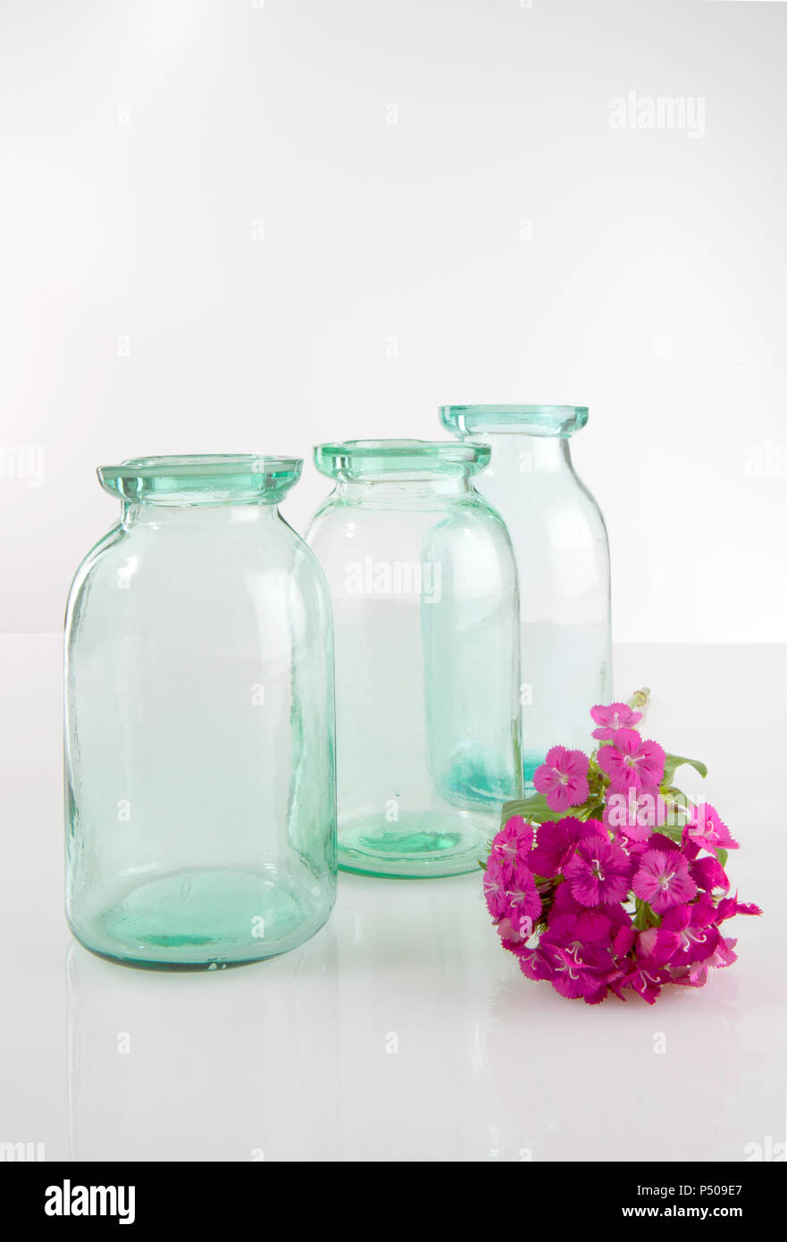 Vintage aqua vasetti di vetro su sfondo bianco con fiori Foto Stock