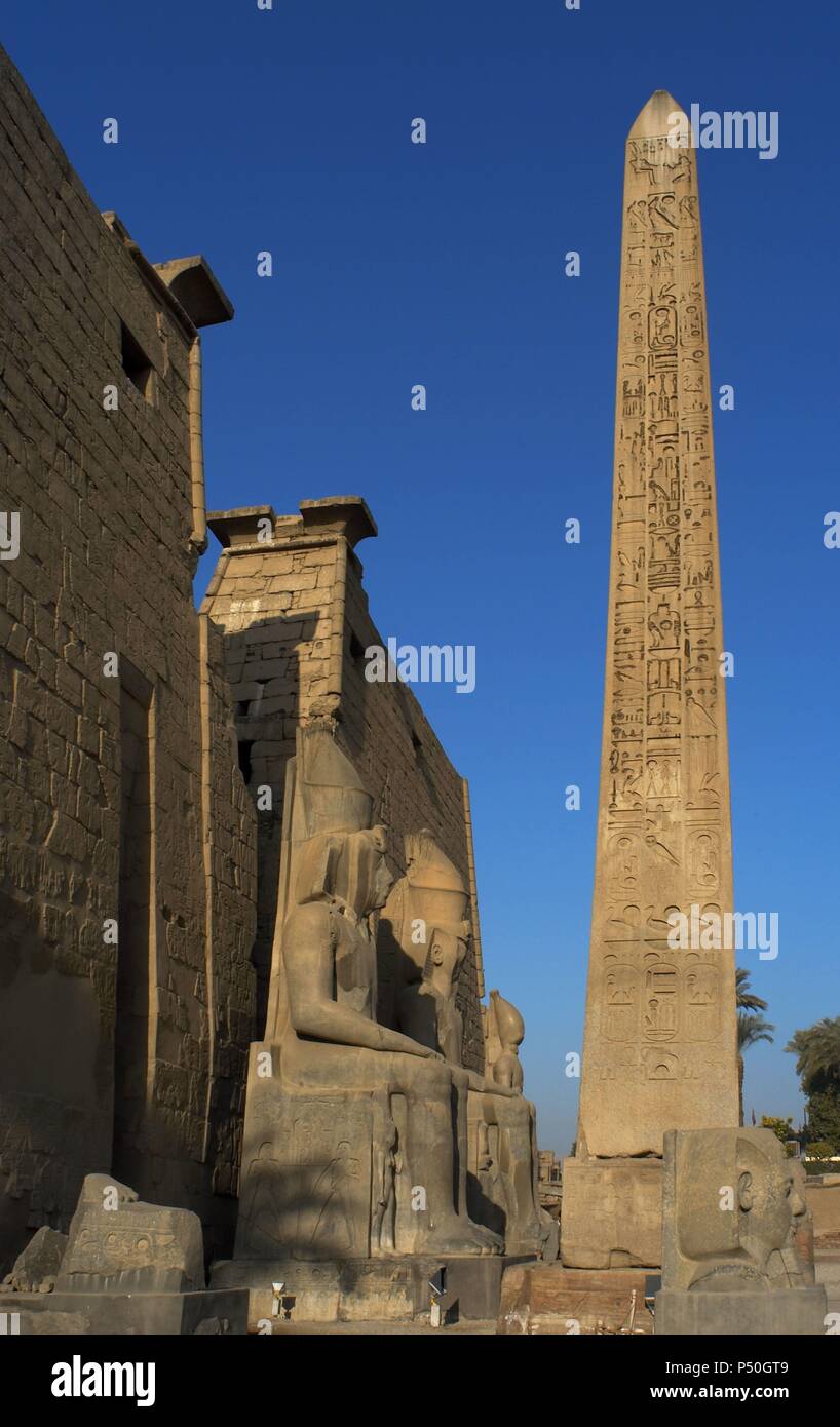 L'Egitto. Tempio di Luxor. Vista parziale del primo pilone del tempio e i resti di un obelisco di granito rosa e la testa e colossali statue di Ramses II. Antica Tebe "Waset,. Foto Stock