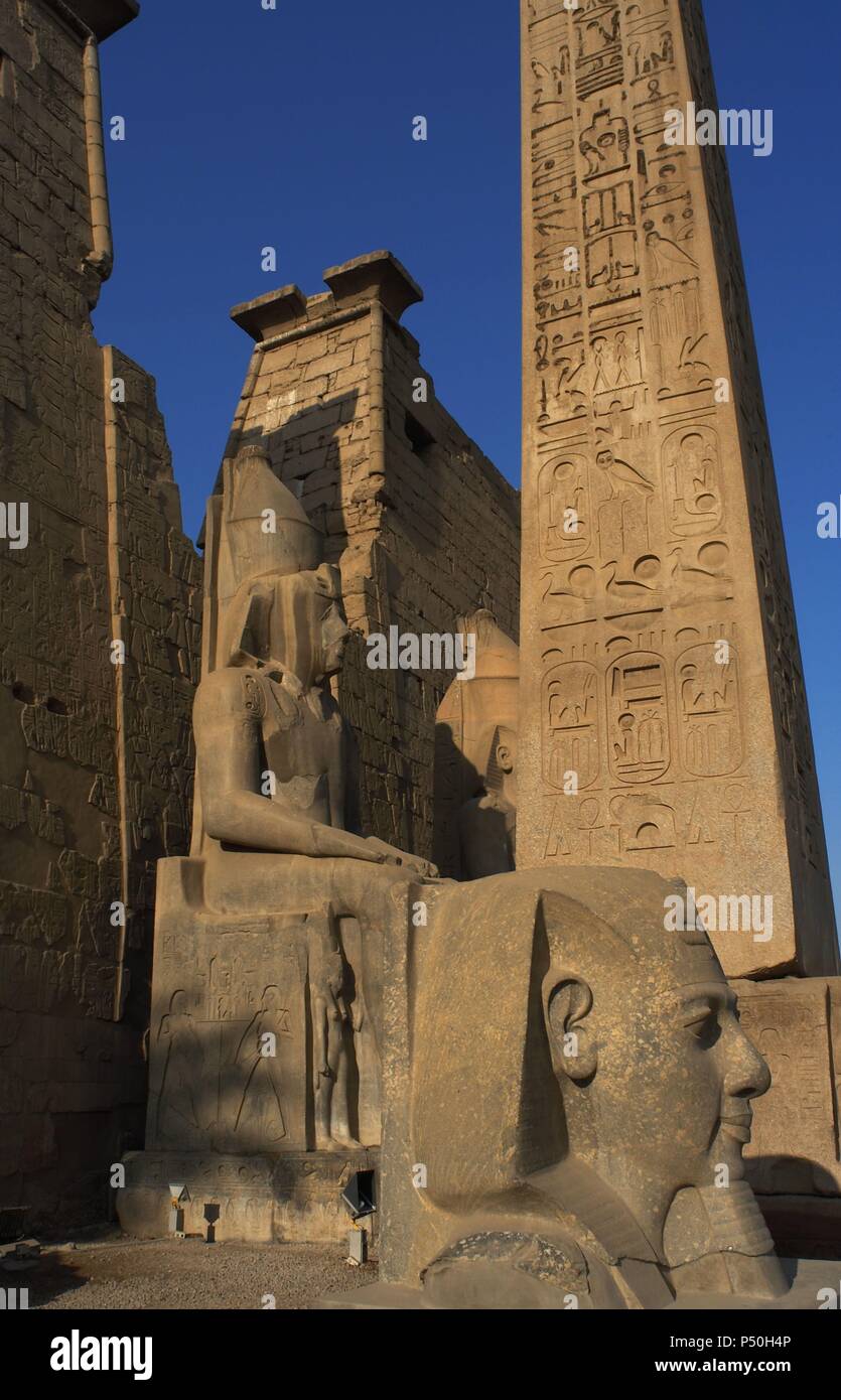 L'Egitto. Tempio di Luxor. Vista parziale del primo pilone del tempio e i resti di un obelisco di granito rosa e la testa e colossali statue di Ramses II. Antica Tebe "Waset,. Foto Stock