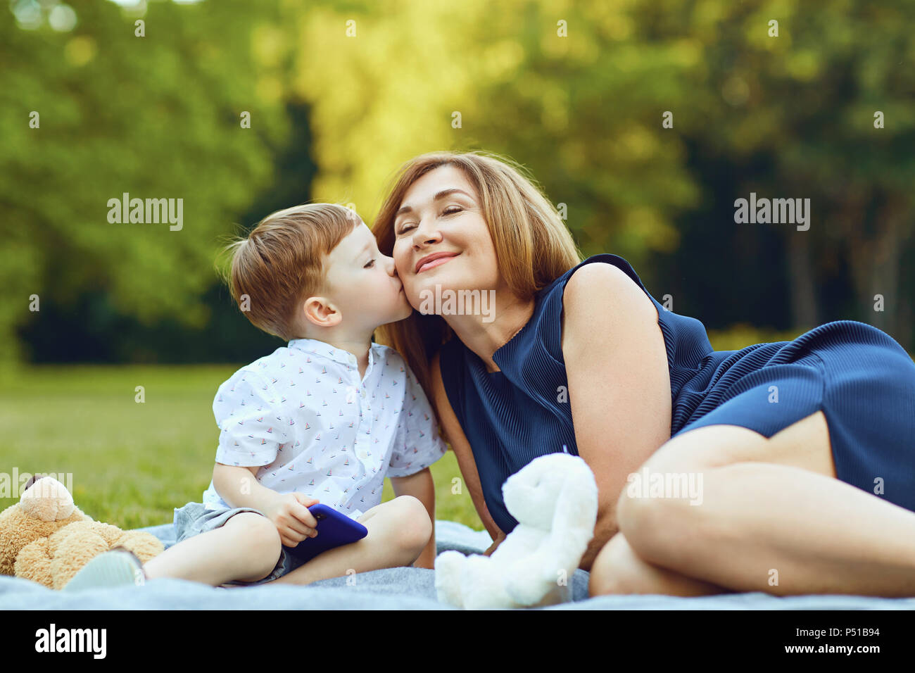 Madre con bambino che gioca sull'erba al tramonto in estate Foto Stock