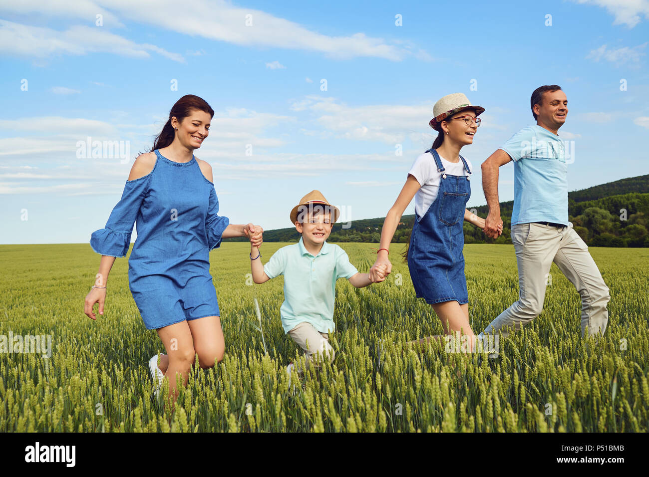 La famiglia felice sorridente in esecuzione sul campo nella natura Foto Stock