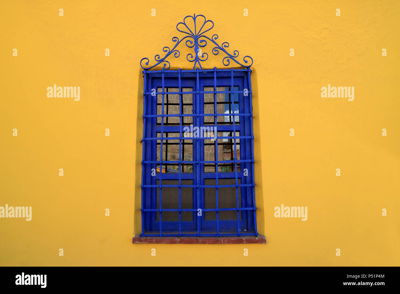 Vivid Blue vetro artistico sulla vibrante parete gialla Foto Stock