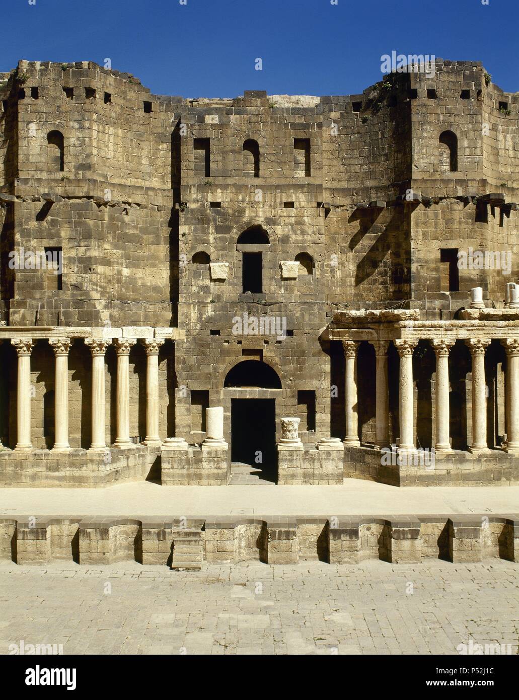 ARTE ROMANO. PROXIMO ORIENTE. SIRIA. TEATRO ROMANO DE BOSRA. Construido a finales del siglo II d. C., en el periodo tardo romano. Vista generale de la fachada del ESCENARIO (SCENARIUM), decorado con columnas de marmol. En primer término, el muro del proscenio (PROSCAENIUM). BOSRA. Foto Stock