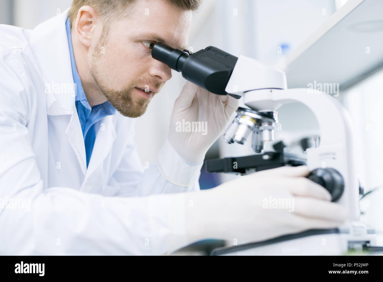 Microbiologo stupito guardando all'oculare del microscopio Foto Stock