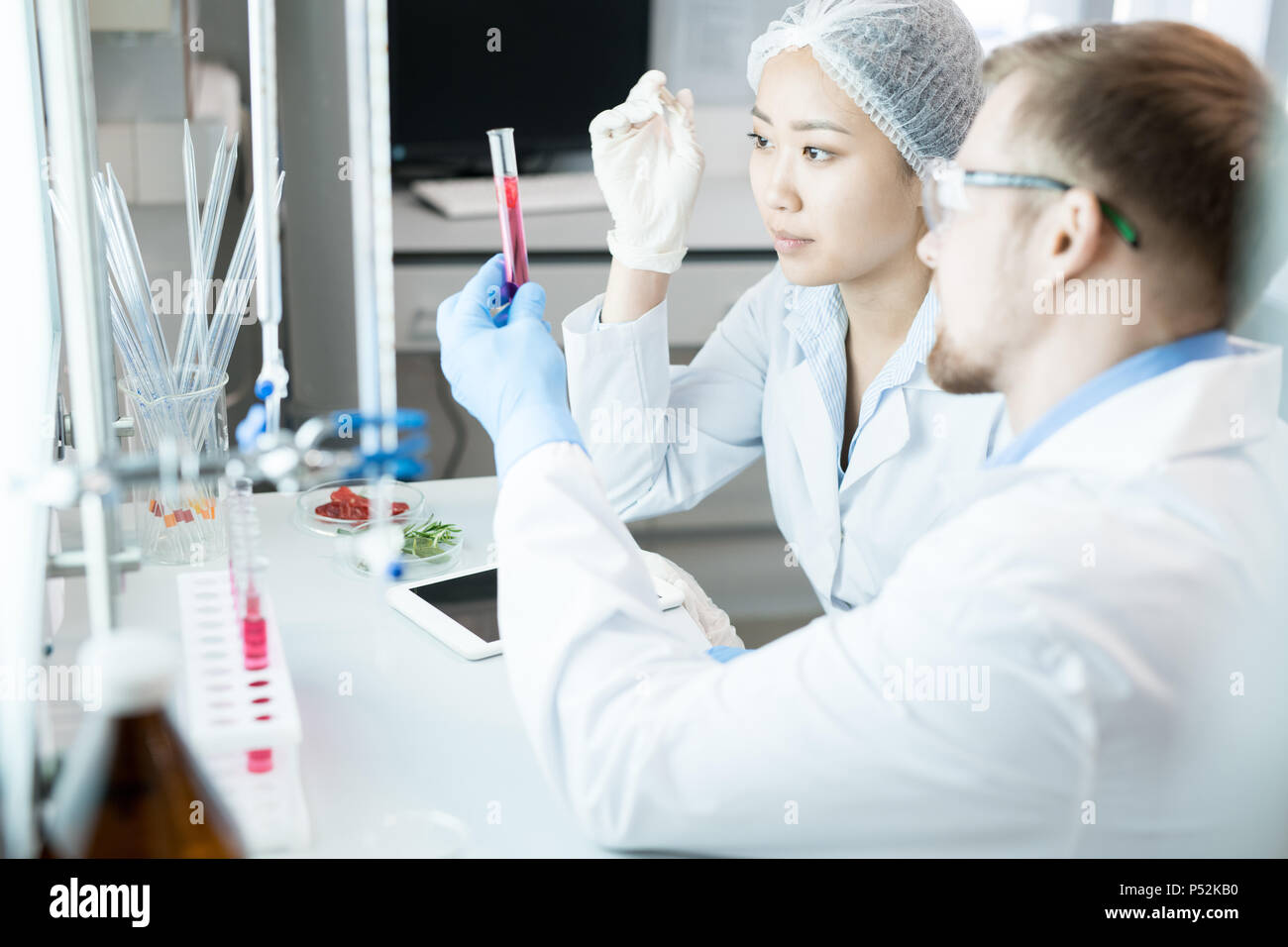 I microbiologi osservando il test di vetro con liquido rosa Foto Stock