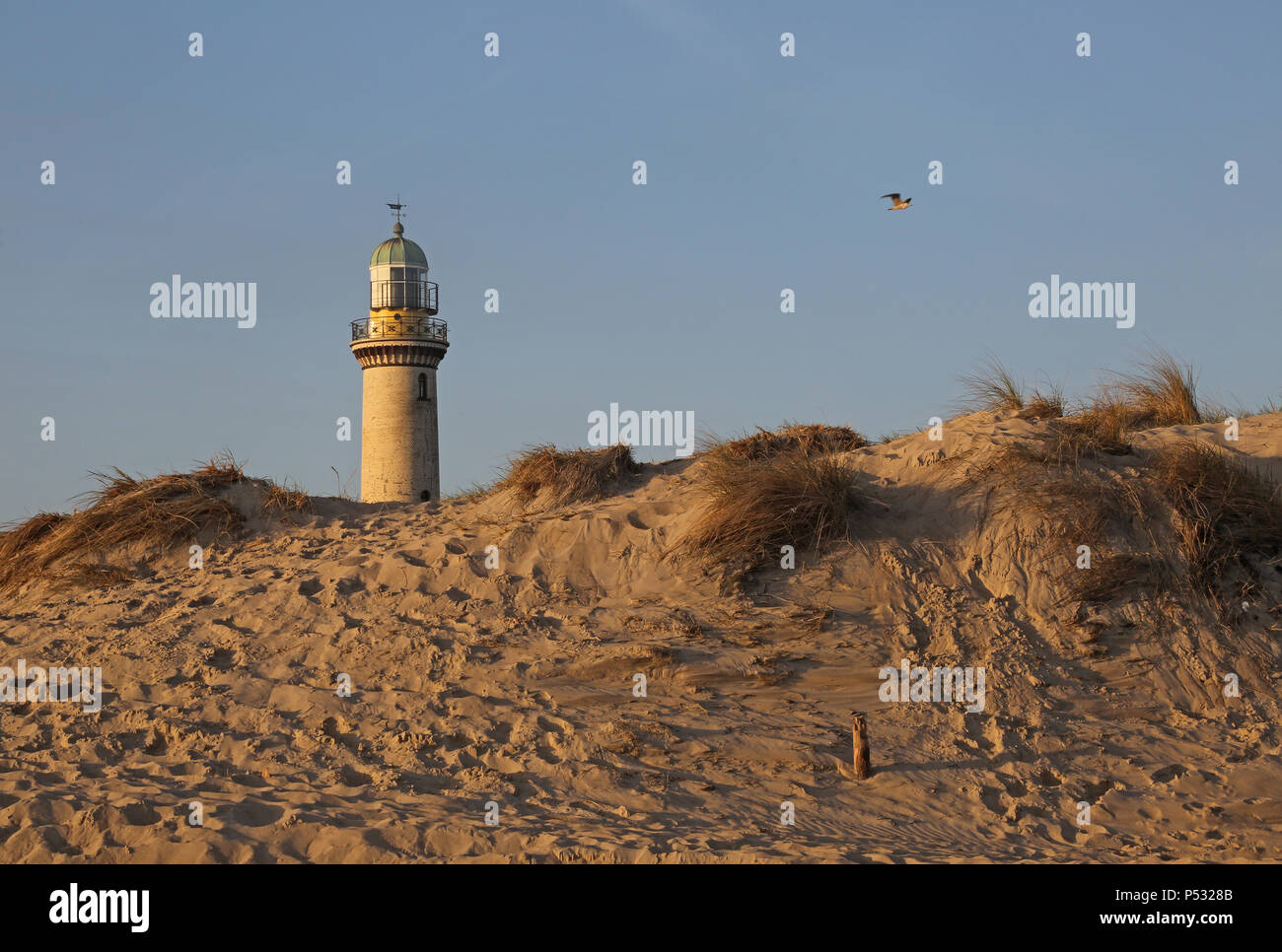 Warnemuende, faro dietro una duna di sabbia al mattino Foto Stock
