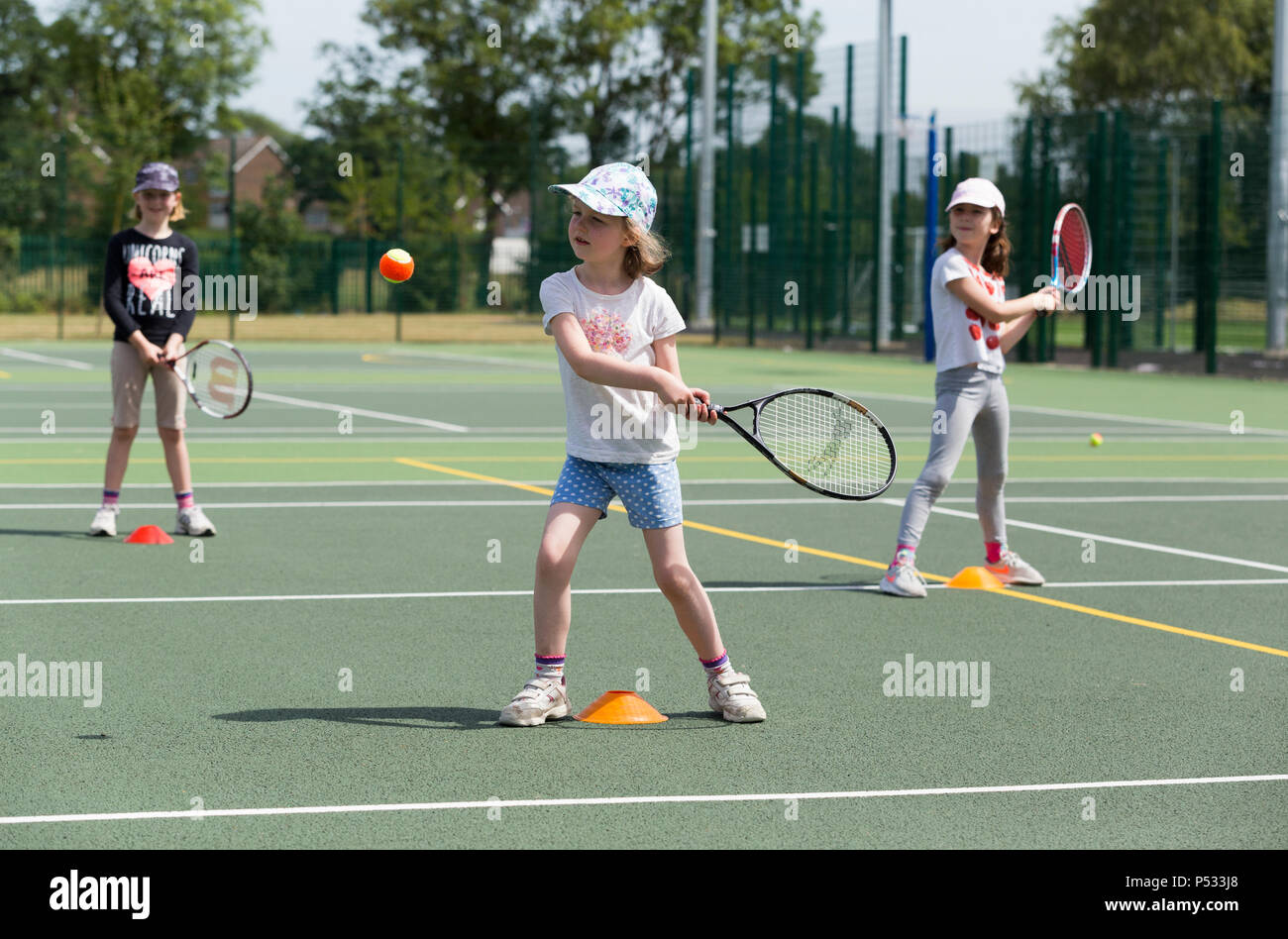 Tennis per bambini la sessione di coaching / lezione che si svolge su una full-size campo da tennis con i bambini / bambini e professional tennis pullman, in estate. Regno Unito. (99) Foto Stock