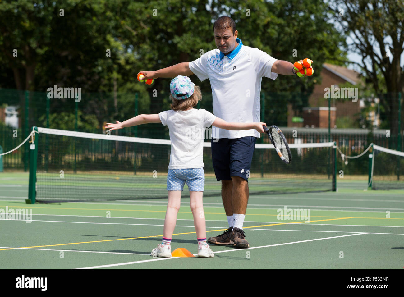 Tennis per bambini la sessione di coaching / lezione che si svolge su una full-size campo da tennis con i bambini / bambini e professional tennis pullman, in estate. Regno Unito. (99) Foto Stock
