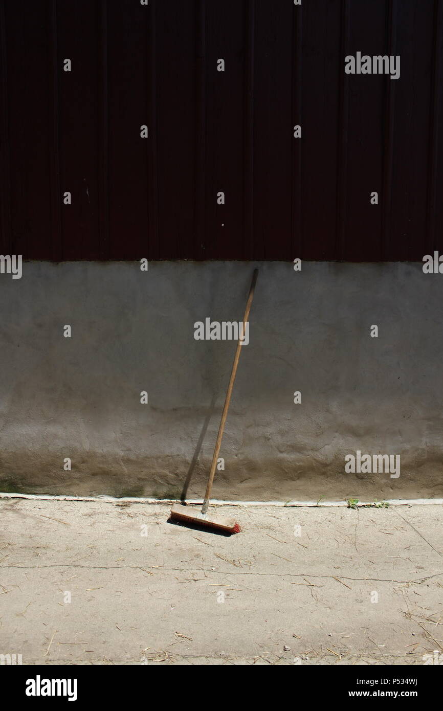 Una spazzatrice che si erge contro una parete rustica. Foto Stock