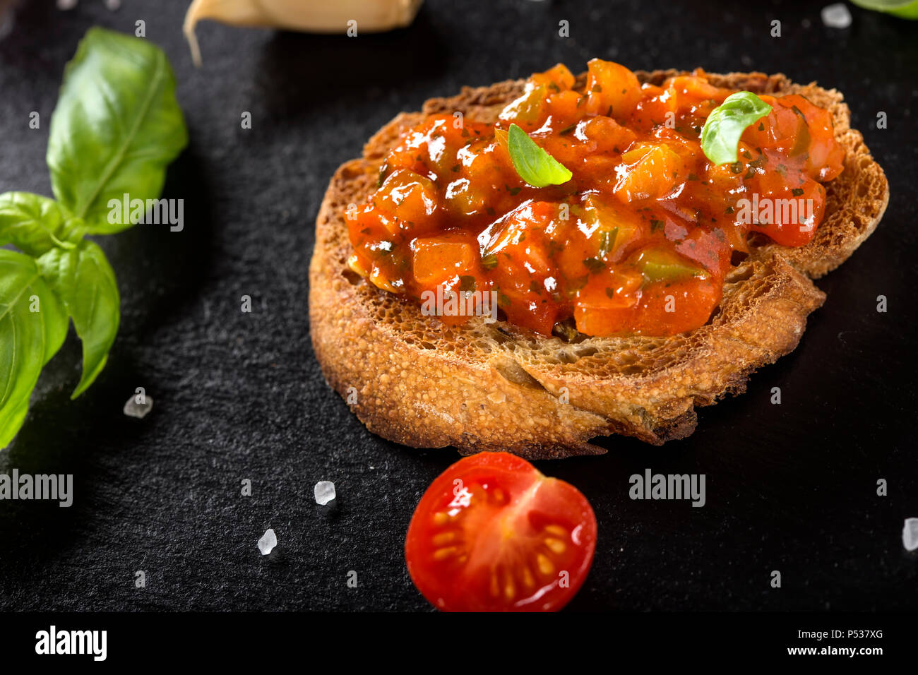 Antipasto Italiano chiamato Bruschetta condito con pomodoro, aglio, pepe rosso e basilico - Vista ravvicinata Foto Stock