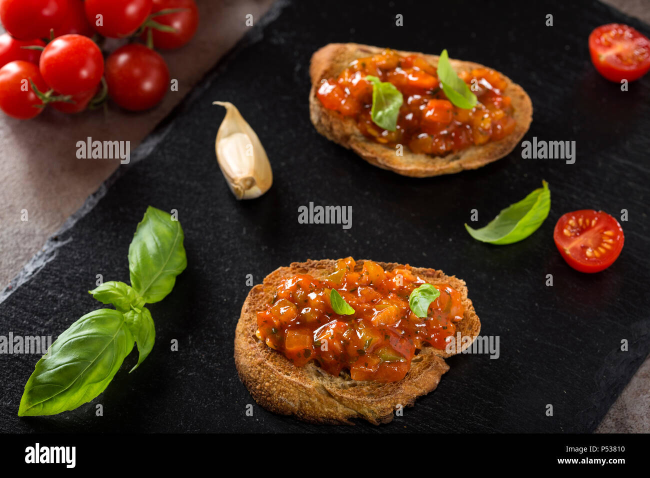 Freschi Fatti in casa italiana croccante antipasto chiamato Bruschetta condito con pomodoro, aglio, pepe rosso e basilico Foto Stock