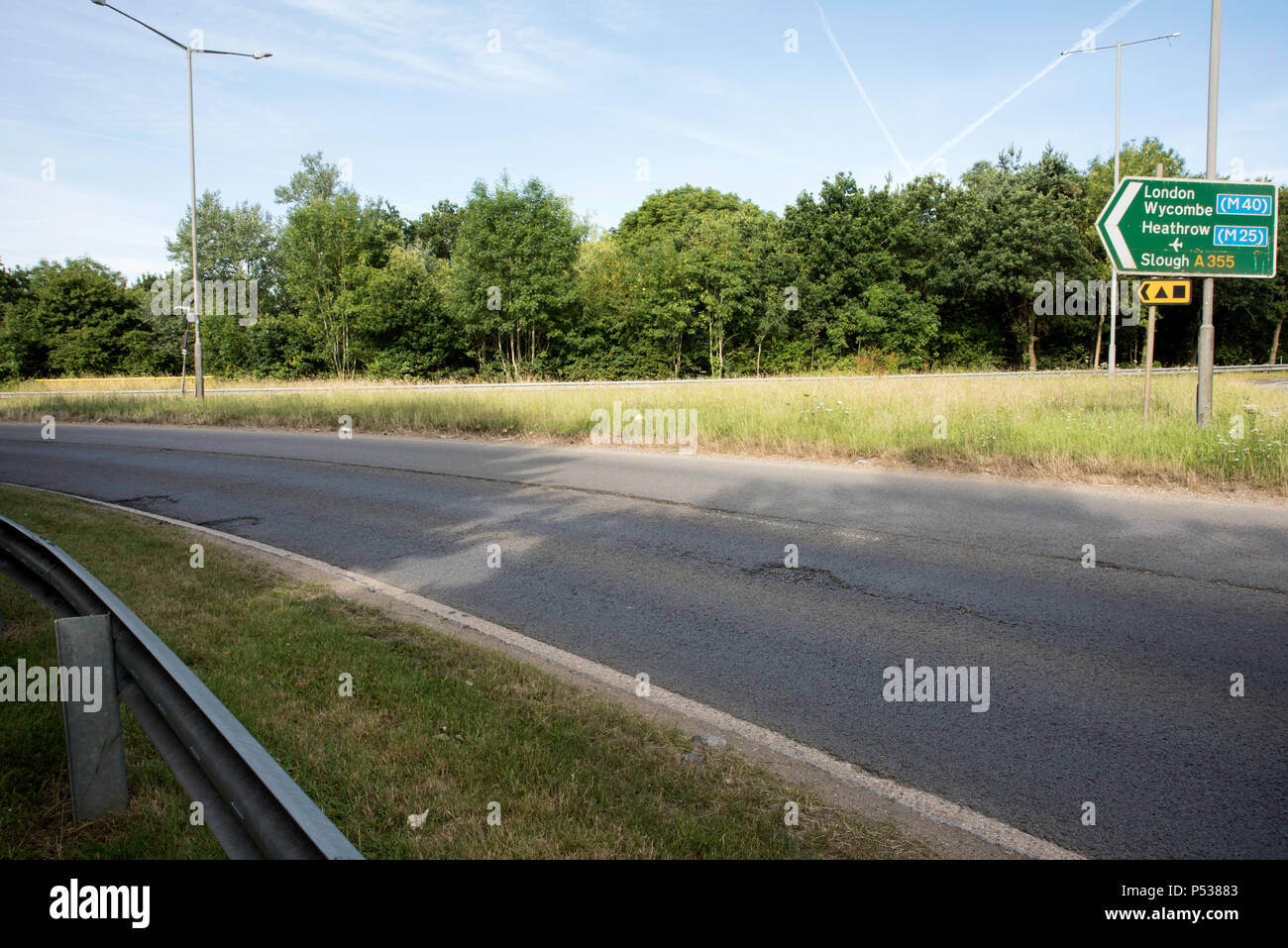Cattiva strada su superfici di le strade della Gran Bretagna. Giunzione di Pyebush rotonda e A355, Beaconsfield. Rivolta verso il filo di acciaio inossidabile. Foto Stock