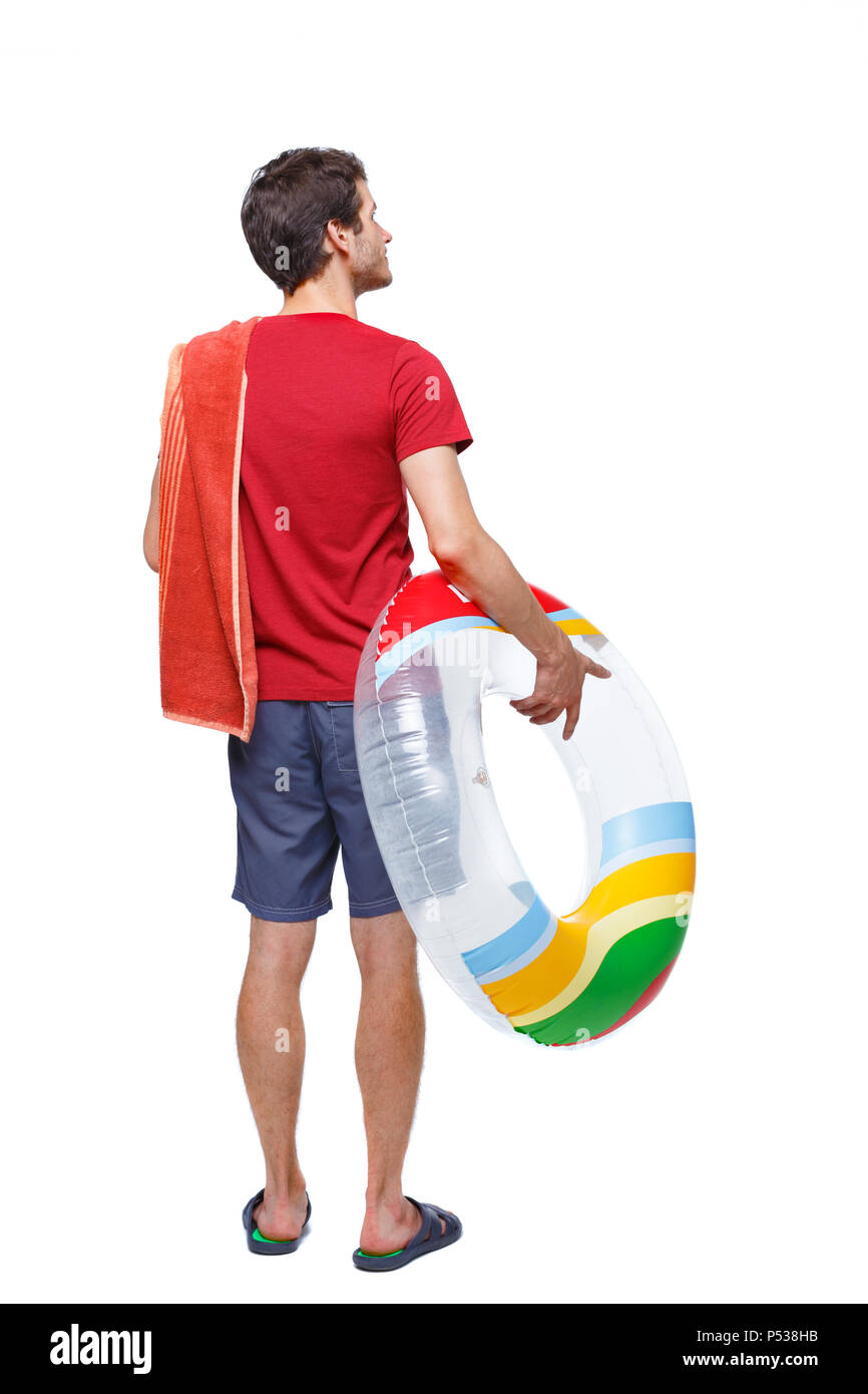 Vista posteriore di un uomo in pantaloncini corti con un cerchio gonfiabile. Il ragazzo sulla spiaggia. Vista posteriore di raccolta persone. vista posteriore di persona. Isolate su wh Foto Stock