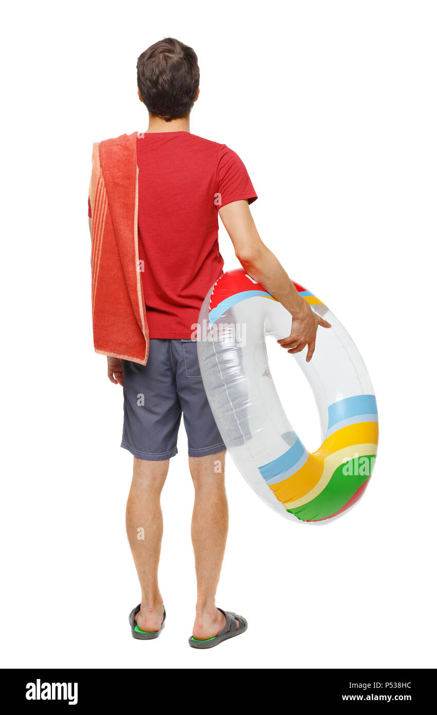 Vista posteriore di un uomo in pantaloncini corti con un cerchio gonfiabile. Il ragazzo sulla spiaggia. Vista posteriore di raccolta persone. vista posteriore di persona. Isolate su wh Foto Stock