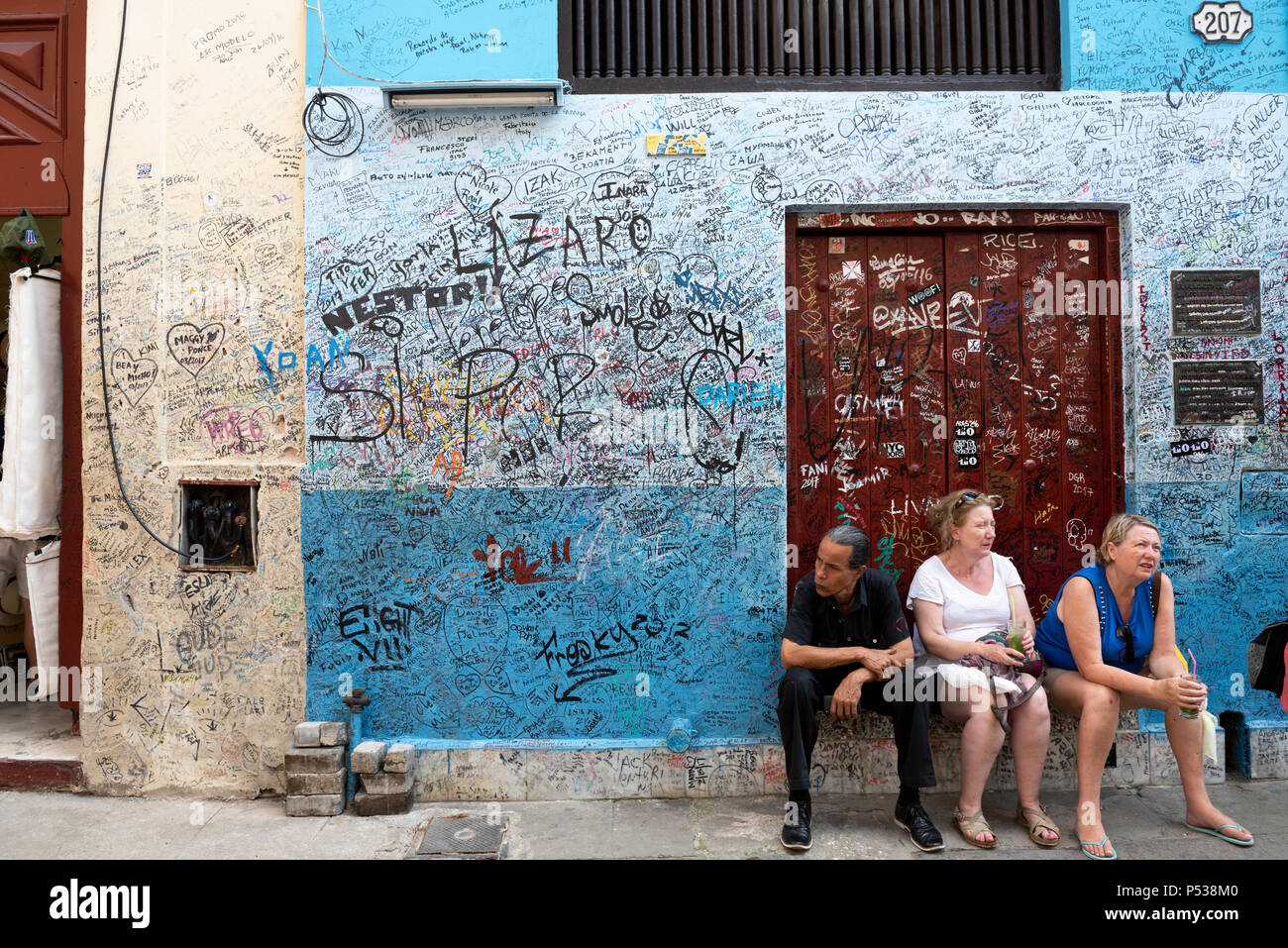 Le persone sono seduti sulla soglia di casa al di fuori della famosa La Bodeguita del Medio bar-ristorante a l'Avana, Cuba. Foto Stock
